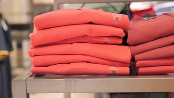A stack of red shirts on a shelf in a store video