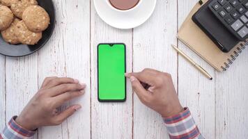 Man using smartphone with green screen on wooden table video