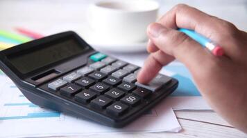 A man using a calculator to calculate the cost of a project video