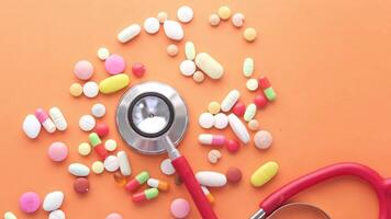 A stethoscope and a pile of pills on an orange background video