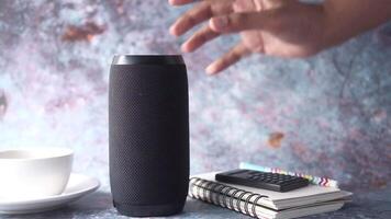 A person is reaching for a speaker on a table video