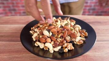A person is holding a plate of mixed nuts video