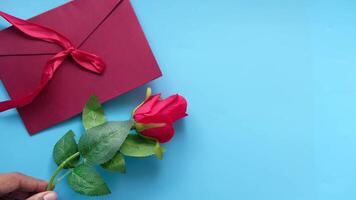 Valentine's day concept with red rose and envelope on blue background video