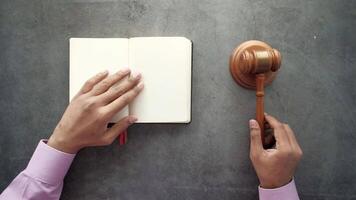 Hands holding a gavel and a notebook on a concrete wall video