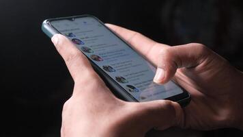 A person's hand holding a smartphone with social media on the screen video