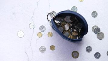 A coin purse with coins scattered on a white surface video