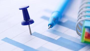 A blue pen is placed on top of a paper with a graph video