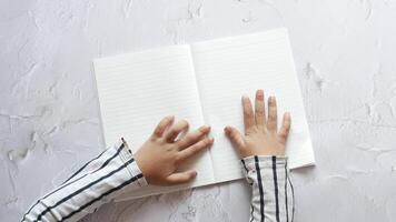 Top view of a child's hands writing on a blank notebook video