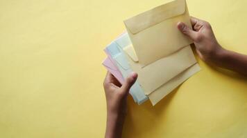 A person holding a stack of envelopes on a yellow background video