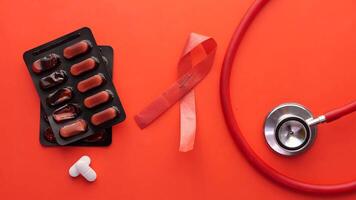 A stethoscope, red ribbon and pills on a red background video