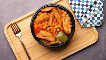 Chicken and chickpeas in a bowl with a fork on a wooden table video