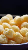 An enticing closeup view of golden corn puff snacks beautifully arranged in a pristine white bowl video