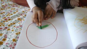 A child is engaged in the creative activity of making art using a crayon on paper video