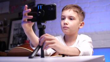close-up boy learns to play guitar using online courses on his phone app video