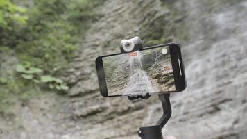 Shooting a waterfall on a new iPhone. Action. A new phone model mounted on a tripod that removes falling water drops from the mountains. Use only for editorial. video