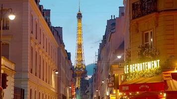 France, Paris - July 24, 2022. Beautiful view of Eiffel Tower. Action. Beautiful European street with yellow lights and cafes. Picturesque view of Eiffel Tower through evening streets of Paris video