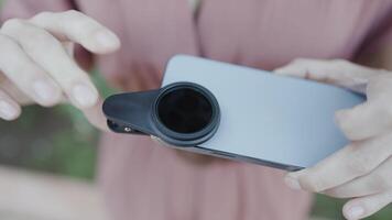 Close up of woman putting removable lens for smartphone on its camera. Action. Concept of technologies. video