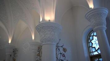 A light white building with dim lighting. Scene. Huge white decorated columns with soft orange illumination. video