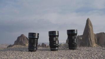 Three professional camera lenses. Action.Large black lenses from the camera that stand on the road of stones and you can see the gray sky. video