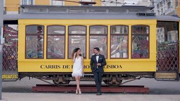 Tourist street. Lisbon- Portugal, 06.12.2022. Action. Young people in summer outfits pose in front of a statue of a tram car. Use only for editorial. video