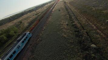 Drone is moving behind train. Shot. Top view of drone following train. Cinematic movement behind fast moving train on background of fields and sun video