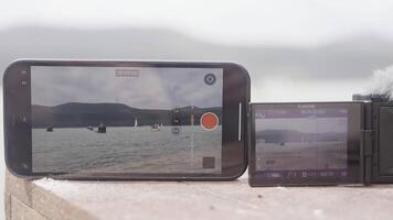 Turkey, Istanbul - August 10, 2022. Comparing videos on phone and camera. Action. Close-up phone screens and cameras capture landscape. Comparison of recording on phone and camera