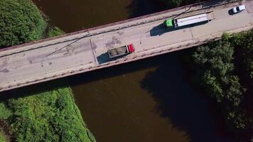 A view over a place for cars to move over a dirty river. Clip.A bird's-eye view of moving trucks over the river and forests around. video