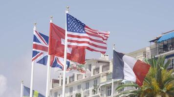 Row of waving flags of different countries. Action. Concept of politics, waving flags on a blue sky and building background. video