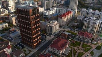 Top view of modern design of building on background of city. Stock footage. Modern city with beautiful architecture and modern business buildings. Golden edition with offices on background of city in video