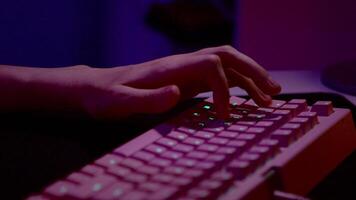 Close up of fingers of a man pressing buttons of a computer keyboard. Stock footage. Dark room with pink lighting. video