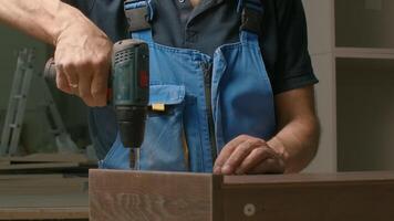 Close up of a man carpenter using screwdriver while working with a wooden product. Creative. Woodwork at the workshop. video