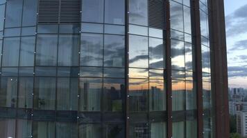 Top view of sunset reflection in windows of business high-rise. Stock footage. Modern skyscraper with glass windows and reflection. Reflection of city and sunset in windows of business building video