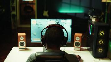 Man playing SF videogame on PC screen, shooting asteroids, putting headphones on. Close up of gamer enjoying spaceship flying game on computer desktop display, navigating through meteorites, camera B video