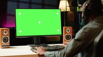 Gamer using headphones to discuss with mates while playing online videogame on isolated screen monitor. Man enjoying coop game with friends on mockup computer display, chatting on internet video