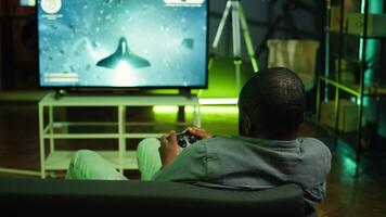 Man playing SF videogames on gigantic smart TV, relaxing after long day at work. Competitive gamer having fun on gaming console in apartment, piloting spaceship using controller, camera B video