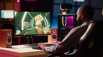 Man having fun by playing videogames on gaming PC at computer desk, enjoying day off from work. Gamer battling enemies in online multiplayer shooter from the comfort of his home, camera A video