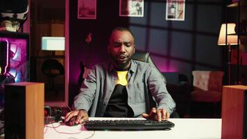 Man in neon lit apartment playing intense videogames on gaming PC at computer desk. Gamer competing against enemies during internet multiplayer competition, unwinding at home, camera B video