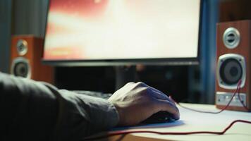 Gamer using keyboard and wired mouse to play videogames on desktop PC, close up shot. Man playing online game in front of monitor with computer peripherals at desk in apartment, camera B video