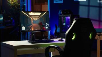 Neon lit components on opened gaming PC device next to keyboard, speakers, wired mouse and headphones in empty apartment. Computer in home with colorful gpu and cpu parts, panning shot video