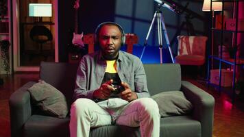 Annoyed man shouting after losing while playing online multiplayer videogame, frustrated by unhelpful teammates. Gamer raging after receiving game over message, upset with noob friends, camera B video