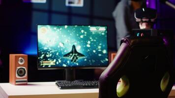Man coming home to play SF space videogame on PC screen after finishing job shift. Gamer entering room, starting spaceship flying game on computer in RGB lit home late at night, camera A video