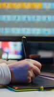 Vertical Photo editor using graphic tablet to edit color balance, delivering appealing photographs for magazines. Close up on graphic designer using stylus on touchscreen device to modify images, camera B video