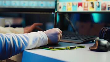 Photo editor using graphic tablet to retouch photographs with editing software on, zooming in to find spots that need correcting. Photographer in creative workplace adjusting images, camera A video