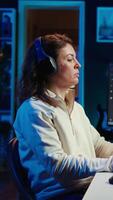 Vertical IT programmer listening music while fixing vulnerabilities in software compromising operating system. Cybersecurity expert wearing headphones and using PC to patch security exposures, camera B video