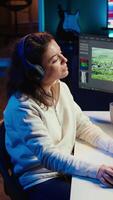 Vertical Freelancer adds sound effects to filmed footage, working in home studio. Post production specialist using headphones to test and improve audio quality using editing application, camera B video