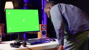 Gamer using keyboard and mouse to play videogame on gaming PC isolated screen monitor. Man in apartment at night using high tech computer peripherals to defeat foes on mockup display video