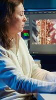 Vertical Upbeat videographer reviewing footage and selecting scenes, trimming using specialized software applications and editing tools. Smiling editor working for media company in editing room, camera A video