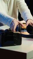 Vertical Photo editor editing images lighting and color balance, delivering visually appealing final product, listening to music. Freelancer wearing headphones, browsing through photographs, camera A video
