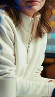 Vertical Portrait of happy photo editor color correcting photographs in creative studio next to cup of coffee on desk. Joyous photographer selecting best pictures for editorial content, camera A video