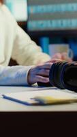 Vertical Freelancer editing images lighting and color balance, working in home studio while enjoying music. Photographer using headphones to listen favorite songs while using retouching software, camera A video
